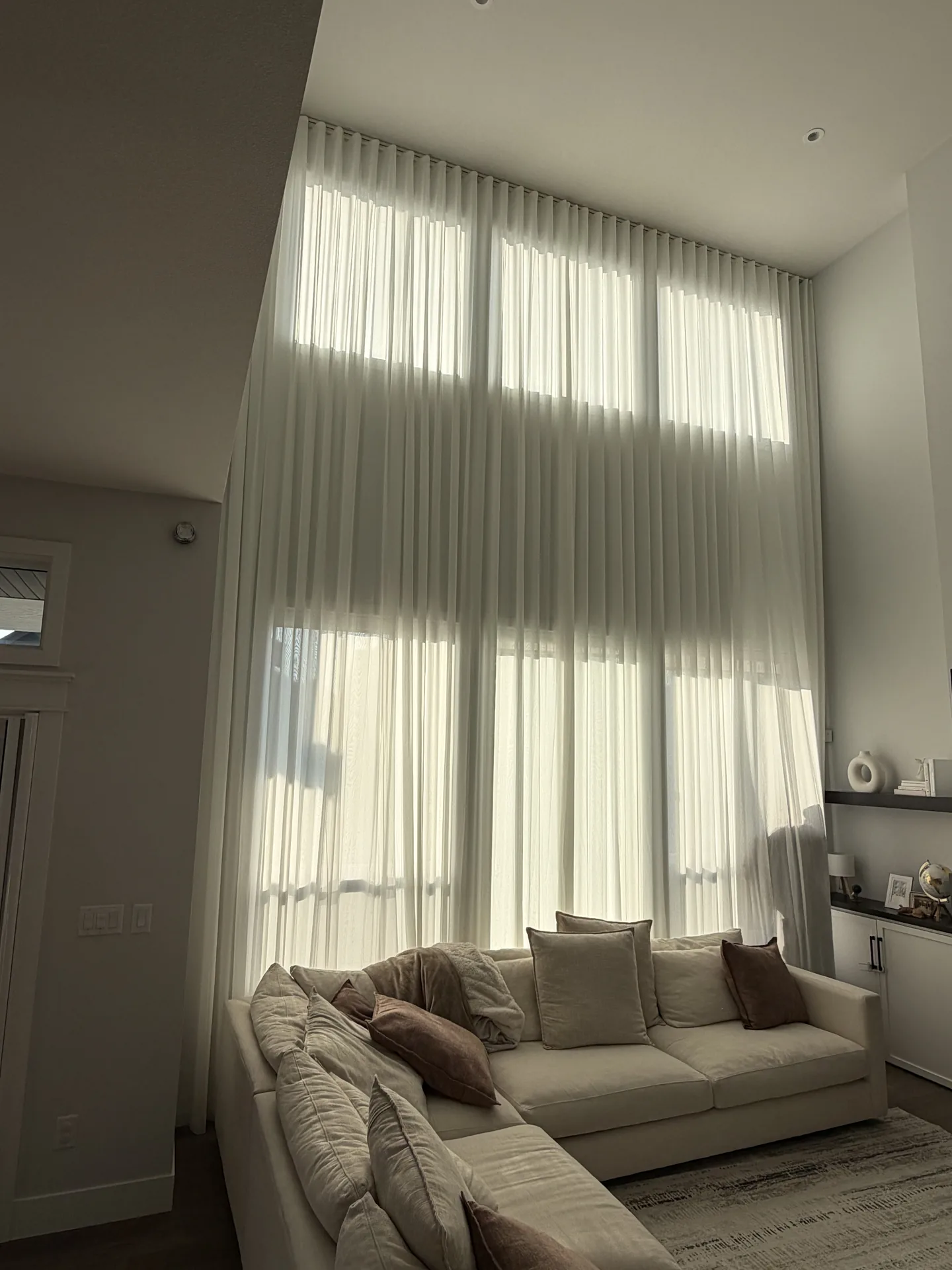 Floor-to-ceiling sheer drapes in a double-height living room